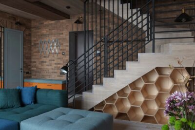 Der Stauraum unter der Treppe nutzt den ansonsten ungenutzten Platz perfekt aus und bietet in einem stilvollen Wabenmuster viel Platz für Bücher oder Dekor. Der elegante schwarze Metallhandlauf der Treppe verleiht dem Raum eine moderne und industrielle Note. Foto: Yevhenii Deshko by unsplash