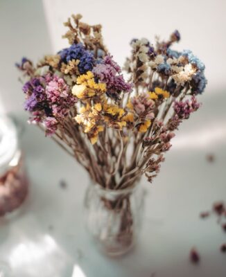 Ein kunstvoll arrangierter Strauß aus getrockneten Blumen, darunter Lavendel und Gänseblümchen, präsentiert in einer einfachen Glasvase verschönert jede Küche. 