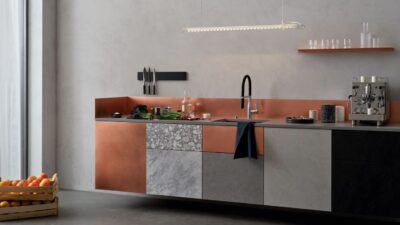 Der interessante Fronten-Mix fällt gleich ins Auge. Unter anderem gehören die matten Fronten in Kupfer dazu, das lässt die eher puristischen Fronten in Grautönen gemütlicher anmuten. Richtig schick ist auch die kupferfarbene Ummantelung der Arbeitsfläche. Die Armatur „Sync“ im Industrial-Style ist von Dornbracht.