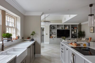 Die Küche im Shaker-Stil steht für das moderne Landhaus. Das helle Grau ist ein derzeit sehr angesagter Ton. Die Keramikspüle, die matte Armatur und die Griffe sind ein Eyecatcher. Letztere sind von Armac Martin.