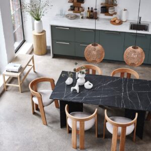 Tisch „Krondal“ fällt auf und markiert deutlich den Essplatz. Umso schöner ist die Ergänzung mit Rattan und Holz in Form von Stühlen und der Lampe. Das nimmt dem Tisch die Schwere. Die gerundeten Stühle „Bovrup“ aus Eiche haben das Zeug zum Klassiker. Beides von Jysk