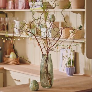 Wenn die Vase schon ein Hingucker ist, müssen die Zweige nicht unbedingt komplett geschmückt sein. Selbst ohne Deko sehen sie toll aus, vor allem wenn rundherum die Accessoires österlich sind. Niedlich ist die Lichterkette am Küchenregal, alles von Søstrene Grene.