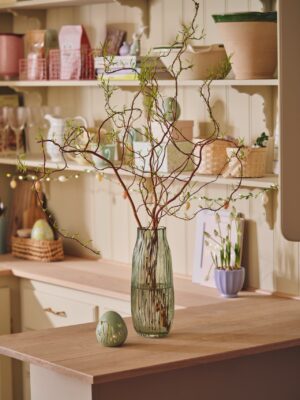 Wenn die Vase schon ein Hingucker ist, müssen die Zweige nicht unbedingt komplett geschmückt sein. Selbst ohne Deko sehen sie toll aus, vor allem wenn rundherum die Accessoires österlich sind. Niedlich ist die Lichterkette am Küchenregal, alles von Søstrene Grene.