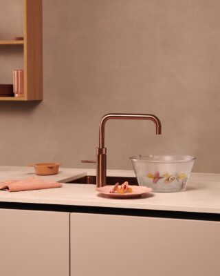 Die Armaturen von Quooker sind echte Zauberkünstler. Aus ihnen kann man nicht nur heißes Wasser für Tee bekommen. Das Gerät ist auch mit einer Kindersicherung ausgestattet. Hübsch ist der Wasserhahn in der Farbe „Rose Copper“.  
