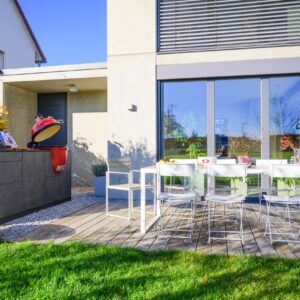 Auf einem Bett aus Kieselsteinen ist die Küche toll platziert. Praktisch ist auch die Nähe zum Haus. Die Küche von Out4Kitchen wird in der eigenen Manufaktur gefertigt. Ein echter Hingucker ist das rote Grill-Ei aus Keramik.