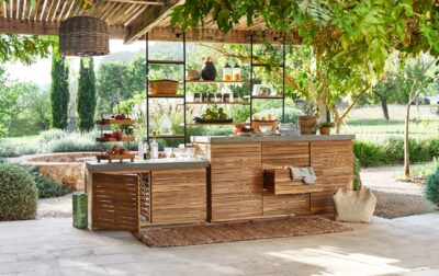 Die Holzkonstruktion der Outdoor-Küche von Loberon begeistert mit ihrem rustikalen Charme und kommt dennoch zeitgemäß daher mit den Boho-Elementen. Auf der großzügigen Arbeitsfläche lassen sich Gerichte gut zubereiten.