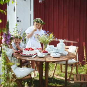 Frische schwedische Erdbeeren sind der süße Höhepunkt des Mittsommerfestes. Alternativ gibt es Erdbeertorte oder Erdbeer-Rhabarber-Crumble mit Vanillesauce. Super sieht es aus, bei einem schwedischen Fest einen Blumenkranz zu tragen. Möbel und Geschirr von Ikea.