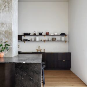 “Smoked Oak” heißt die Holzfarbe der Küchenzeile von Reform. Elegant wird sie von Goldakzenten in Szene gesetzt. Raffiniert ist die Insel, die um die Vintage-Säule herumgebaut wurde.