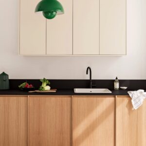 Die stylishe Flowerpot-Lampe in kräftigem Grün beweist, dass auch nur ein Farbakzent den Raum lebendiger macht. Die Küche selbst begeistert dennoch mit der geschmackvollen Farbkombi aus Weiß, Holz und Schwarz, von Plum Living.