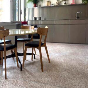 Ein perfektes Ensemble ergibt sich aus Regal, Rückwand und Küchenzeile aus Edelstahl. Die Einheit wirkt klar und ruhig. Gemütlich gestaltet wird das Ganze mit weiteren Möbeln und mit dem Terrazzo-Boden von Via.