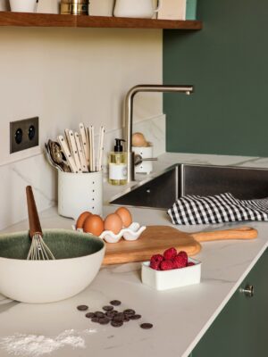 Eine Arbeitsfläche muss viel aushalten. Teig kneten, das hin- und herschieben von Schüsseln und Backformen und vieles mehr. Da ist es gut, wenn sie robust ist. Die angesagte dünne Arbeitsfläche in Marmoroptik bildet einen super Kontrast zur Küche von Plum Living mit dunkelgrünen Fronten.