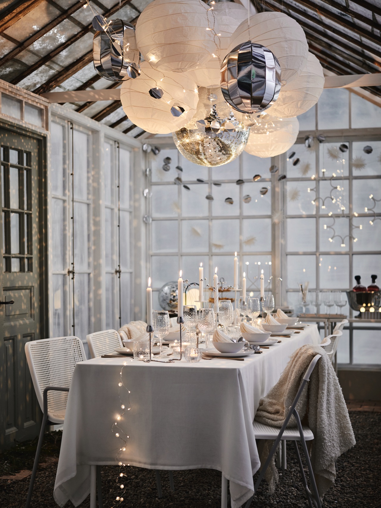 Eine Tischdeko mit Wow-Effekt, denn die Discokugeln und Papierschirme unter der Decke machen richtig etwas her. Wenn Ihre Decke nicht so hoch ist, sind etwas kleinere Lampions ideal. Das i-Tüpfelchen sind viele zarte Lichter und eine edle weiße Tisch-Gestaltung. Alles von Ikea.