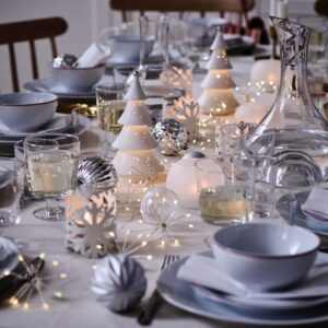 Die moderne Wintertafel strahlt in kühlen Weiß- und Silbertönen. Leuchtende Porzellanbäumchen, funkelnde Kugeln und zarte Lichterketten schaffen eine frostige, festliche Eleganz. Das schlichte Geschirr ist in jeder Saison ein perfekter Begleiter, von Ikea.