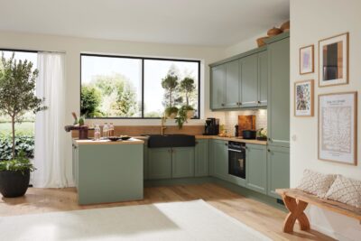 Küche „Camo“ von Mondo zeigt sich in mattem “Schilfgrau” in Lacklaminat. Das verleiht dem Cottage-Stil neue Frische. Auch die typischen Rahmenfronten sehen durch die klaren Linien modern aus. Edel ist die Kombi mit dem schwarzen Keramikbecken plus goldfarbener Armaturen. 