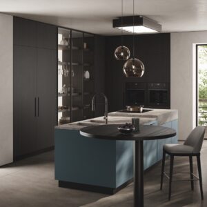 Die „Moda“-Küche von Scavolini beeindruckt. Die Insel verfügt über matt lackierte Türen in „Teal Green“ sowie eine Arbeitsplatte aus Feinsteinzeug. Hübsch ist der Ansatztisch aus Holz-Laminat in edler runder Form.