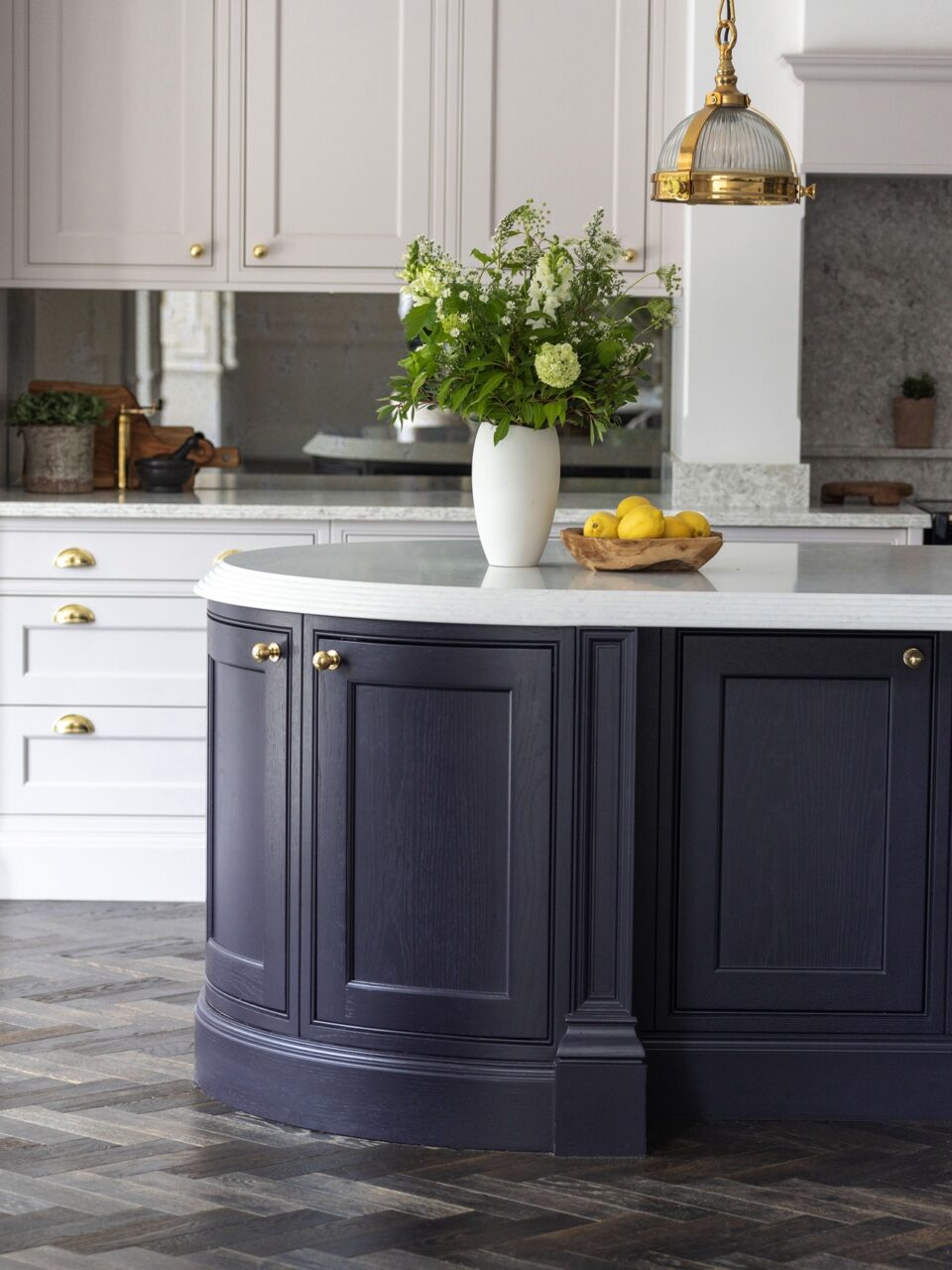 Selbst die Inseltüren sind hier rund. Noch dazu ist der Abschluss der Arbeitsfläche abfallend gerundet. Ein zauberhaftes Landhaus-Ensemble, das wirklich edler nicht sein könnte. Die Farbe trägt ebenfalls dazu bei und die goldfarbenen Griffe von Armac Martin.