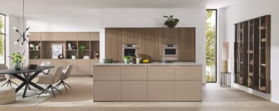 Abwechslung belebt. Die Kochinsel mit pflegeleichter Front „Yoko Silk“ harmoniert sehr gut zur Front im Eichendekor „Neo Rustico“. Nahtlos integriert sich die Küche in den Wohnraum, der mit Möbeln aus der gleichen Serie ausgestattet ist. Beide verschmelzen gekonnt miteinander. Veredelter Stauraum für Gläser, Geschirr und Deko findet sich in geräumigen, seitlichen Vitrinenschränken mit Alu-Rahmenfronten. Alles von Ballerina.