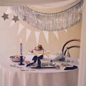 Blau schmeichelt Silber und umgekehrt. Zu Silvester passt auch mal eine kühle Note und die bietet diese Tischdeko. Schleifen sind sehr angesagt. Eine gute Idee ist es, sie um Gläser zu binden. Vorteil: Bei verschiedenen Farbtönen kann sich jeder merken, welches Glas zu ihm gehört. Alles von Søstrene Grene.
