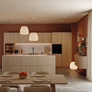 Die Küche von Walden setzt konsequent auf Naturholz, vor allem auf helle Esche. Ganz bewusst spiegeln sich die weichen Linien der Küche im Esstisch wider und sind fast parallel gestaltet. Die grifflosen Fronten verstärken das entspannte Gesamtbild.