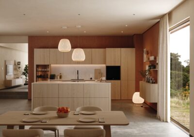 Die Küche von Walden setzt konsequent auf Naturholz, vor allem auf helle Esche. Ganz bewusst spiegeln sich die weichen Linien der Küche im Esstisch wider und sind fast parallel gestaltet. Die grifflosen Fronten verstärken das entspannte Gesamtbild.