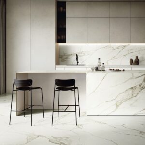 Kontrast als Kontur. Schwarze Armatur, dunkle Leuchte und schwarze Barhocker zeichnen einen zarten Akzent auf die Farbe Cloud Dancer, ohne das Luftige zu verdrängen. Richtig ausgefallen erscheint in diesem Zusammenhang die Marmor-Anmutung, von NovaBell.