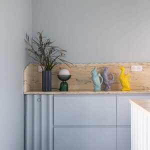 Eine gut organisierte Küche lebt davon, dass jeder Winkel sinnvoll genutzt wird. Die Ecke, die bei der Küche von Plum Living entstand wurde mit einer Front verschlossen, die an einen Vorhang erinnert. Das macht sie außergewöhnlich. Dahinter passt zum Beispiel der Staubsauger. Credit: @amandine.jules / Plum Living