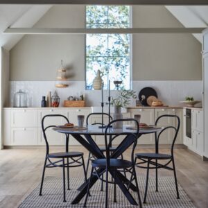 Greige an der Wand und Holz auf dem Boden bringen eine noch wärmere Note in die kuschelige Landhausküche. Die Essecke in Schwarz ist ein hübscher Kontrast dazu. Alles von Affari of Sweden.