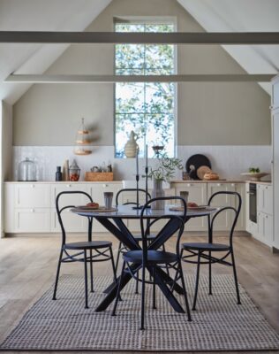 Greige an der Wand und Holz auf dem Boden bringen eine noch wärmere Note in die kuschelige Landhausküche. Die Essecke in Schwarz ist ein hübscher Kontrast dazu. Alles von Affari of Sweden.