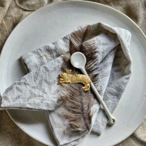 Ein kleines Detail kann den gesamten Tisch bereichern. Hier wird die Stoffserviette kunstvoll gefaltet und mit der Feder und einem niedlichen Hasen-Anhänger ergänzt. Gut sieht es aus, wenn alles Ton in Ton gehalten ist. Alles von Housedoctor.