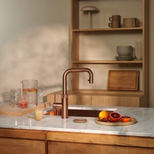 Das massive Holz überzeugt durch schlichte Formen. Edler Marmor und reduzierte Accessoires ebenso. Die Armatur von Quooker in matter Optik ergänzt den anspruchsvollen Farmhouse-Look gekonnt.