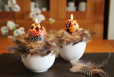 Mit einem Hauch Exotik begeistert das Arrangement mit Kerzen von Nobunto. Die Kerzen werden unter fairen Bedingungen in der Manufaktur in Südafrika hergestellt. Eine süße Ergänzung sind die Federn, die in der Schale drapiert werden.