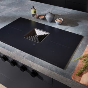 Der Blick liegt auf dem Downline-Abzug. Die zentrale Einströmeinheit optimiert durch die Lamellen das Aufsaugen von Gerüchen. Das klare Design des Kochfel-des von Berbel unterstreicht die matte Optik noch zusätzlich. Hilfreich ist die intuitive Steuerung über ein elegantes Touch-Bedienfeld.