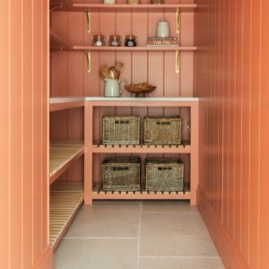 Holzoberflächen und warme Farben schaffen eine besonders ruhige Stimmung. Das gibt dem Raum Eleganz. Die kleine Nebenküche macht schon beim ersten Anschauen gute Laune in diesem warmen Korallenton. Die Arbeitsplatten sind von Quorn Stone.