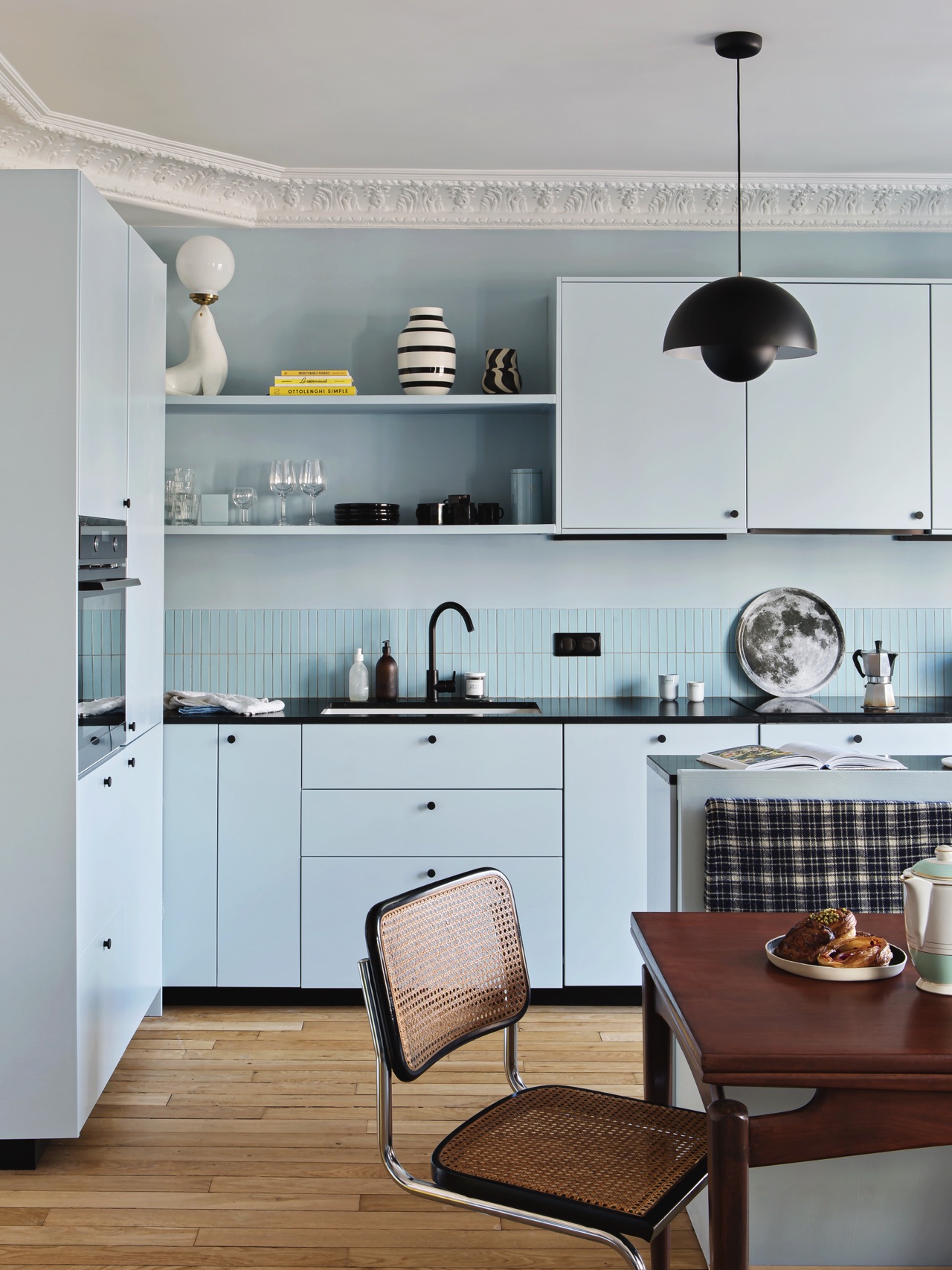 Plum Living setzt in dieser Küche auf den hellen Mattlackton „Ciel voilé“, kombiniert mit schwarzen Details und klassischem Mid-Century-Design. Schwarze Griffe, die Designleuchte „Flower Pot“ sowie antike Stühle verleihen dem zarten Blau mehr Tiefe und grafische Klarheit. | KÜCHEN JOURNAL Plum Living setzt in dieser Küche auf den hellen Mattlackton „Ciel voilé“, kombiniert mit schwarzen Details und klassischem Mid-Century-Design. Schwarze Griffe, die Designleuchte „Flower Pot“ sowie antike Stühle verleihen dem zarten Blau mehr Tiefe und grafische Klarheit.