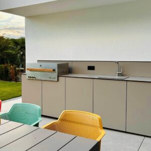 Funktion und attraktives Design verbinden sich bei der Außenküche „Kaarl“ von Unikaad. Fronten ohne Griffe, wetterfeste Materialien und der Grill von Flammkraft, machen sie zu einem Eyecatcher. Das Brett über der Spüle schafft eine zusätzliche Ablage.