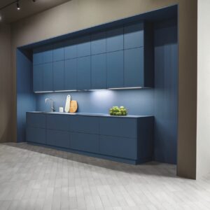 Mit dieser puristischen Küchenarchitektur zeigt next125, wie kraftvoll Blau in minimalistischen Konzepten wirken kann. Die monochrome Planung setzt vollständig auf eine tiefe, matte Blaunuance, die beinahe skulptural erscheint. Denn sowohl die Küchenzeile als auch die Wandgestaltung der Nische sind im soften Farbton gehalten. Durch die reduzierte Linienführung, die grifflose Gestaltung und die indirekte Beleuchtung entsteht eine eigene Raumzone.