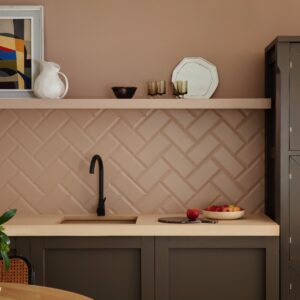 Fischgrätmuster kennt man eigentlich von Parkettböden. Übertragen auf Wandfliesen sieht es überraschend stylish aus und gibt der Küchenrückwand eine architektonische Struktur. Verstärkt wird das durch das zarte Rosa, welches sich auch über die Wand zieht und sogar für das Regalbrett verwendet wurde. Monochrom wirkt es, dass auch die Fugen im gleichen Farbton daherkommen. Wandfarbe „Mochi“ von Little Greene.