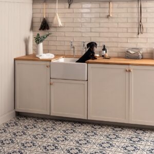 Der gemusterte Boden im matten Finish präsentiert sich im viktorianischen Stil. Das schmeichelt dem Farmhouse-Look der Küche. Gelungen ist die Kombi aus den Porzellan-Bodenfliesen im Farbton „Vogue Dark Blue“ und den reduzierten Wandfliesen. Alles von Original Style.