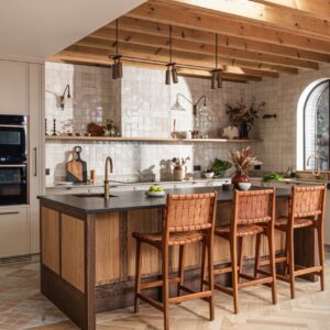 Bei dieser maßgefertigten Küche von Wood Works Brighton bilden die sichtbaren Deckenbalken und die großzügige Kücheninsel eine gelungene Einheit. Helle und dunklere Holznuancen greifen ineinander und sorgen für eine lebendige Wirkung. Die kräftigen Holzstühle verleihen der offenen Küche zusätzlich einen beinahe handwerklichen Charakter.