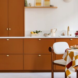 Die Küchenfronten in Caramel von Plum Living machen aus schlichtem Weiß eine wohnliche, farbenfrohe Küche. Helle Flächen und cremefarbene Griffe lassen den Orangeton frisch und modern wirken. Credit: Plum Living / Fotograf ©Hervé Goluza