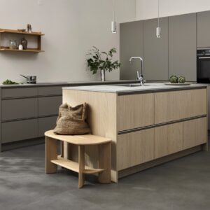 Helle Eiche wird mit sanften Grautönen kombiniert. Im Zentrum steht die Holzinsel, die durch die angestellte Sitzbank ergänzt wird. Das Zusammenspiel der Materialien wirkt leicht, skandinavisch und angenehm ausgewogen. Alles von Kvik.