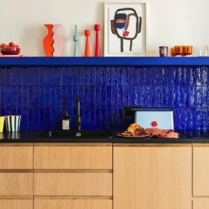 Die Küche von Plum Living beweist, wie wirkungsvoll kräftige Nuancen eingesetzt werden können. Die intensiv blaue Fliesenrückwand bildet einen spannenden Kontrast zu den warmen Holzfronten und den orangefarbenen Accessoires. So entsteht ein dynamisches Farbkonzept, das den Dopamine Style stilvoll interpretiert. | KÜCHEN JOURNAL Die Küche von Plum Living beweist, wie wirkungsvoll kräftige Nuancen eingesetzt werden können. Die intensiv blaue Fliesenrückwand bildet einen spannenden Kontrast zu den warmen Holzfronten und den orangefarbenen Accessoires. So entsteht ein dynamisches Farbkonzept, das den Dopamine Style stilvoll interpretiert.